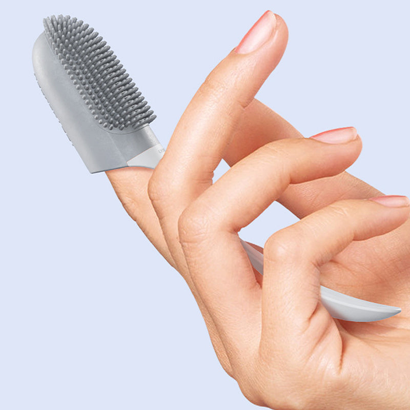 Hand holding a small gray brush against a light blue background