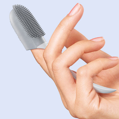 Hand holding a small gray brush against a light blue background